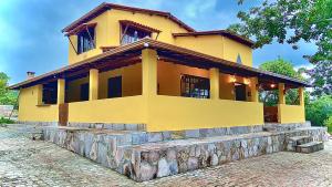 a yellow house with a stone wall in front of it at Casa Abaeté Chapada Diamantina in Mucugê