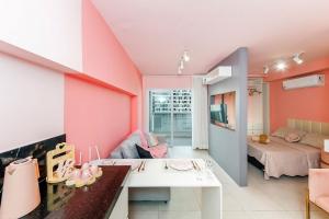a living room with pink walls and a white table at Studio Pink com ar, varanda, academia e piscina in Juiz de Fora