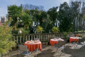 2 tables avec des nappes et des chaises rouges dans un jardin dans l'établissement Best Western Hotel Le Guilhem, à Montpellier