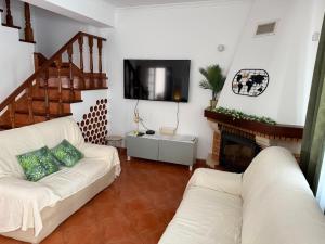 a living room with a white couch and a fireplace at Breeze House Almograve - Rooms on Fishermen's Trail in Almograve