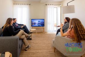 a group of people sitting in a living room watching tv at Hostel Casa São Pedro - Suíte 2 in Angra do Heroísmo