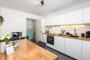 マクデブルクにあるLuxury Vista Apartment I Küche I WLAN I Smart-TV I Zentralの白いキャビネットと木製のテーブルのあるキッチン