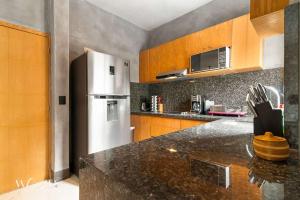 a kitchen with a stainless steel refrigerator and wooden cabinets at Best Spot on 5th Ave - 2BR with King Beds & Style in Playa del Carmen +17 photos