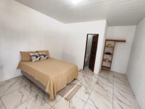 a bedroom with a bed in a white room with marble floors at CAJUÍ da VILA in Atins