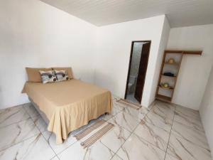 a bedroom with a bed and a mirror and marble floor at CAJUÍ da VILA in Atins