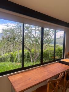 a window with a wooden table and a view of a field at Cabaña Capella Campestre Green in Pinchote