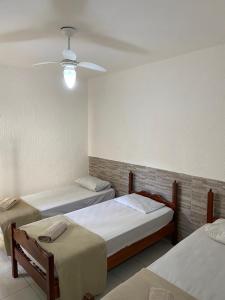 a room with three beds and a ceiling at Pousada nascente do sol in Macaé