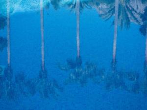 a group of people sitting under palm trees in a pool at Hotel Cala Sant Vicenç - Adults Only in Cala de Sant Vicenc