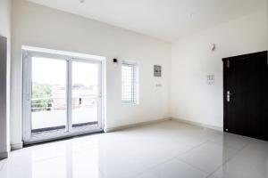 an empty room with a large window and a door at Hotel O Black Pearl Residency in Pīlamedu