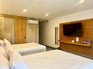 a hotel room with two beds and a flat screen tv at Casa Begonias Hotel mas Villas in Jiutepec