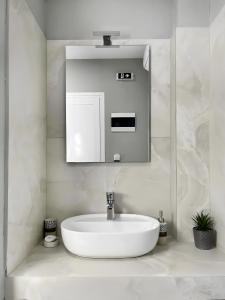 a white bathroom with a sink and a mirror at Marias Apartments in Sarti