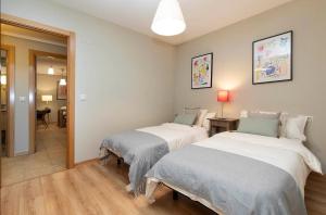 a room with two beds and a hallway at El Bosque del Sapo in El Pueyo de Jaca