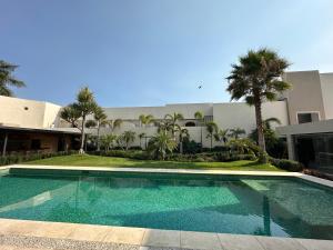 a swimming pool in front of a building with palm trees at Casa Begonias Hotel mas Villas in Jiutepec