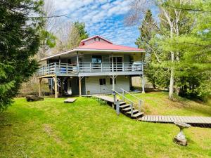 a large house with a porch and a deck at Stunning all season Cottage surrounded by nature! in Brighton