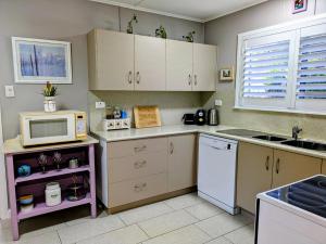 a kitchen with white cabinets and a microwave at Cute Cottage - 2 Bedrooms - City & Strand Beach Location in Townsville