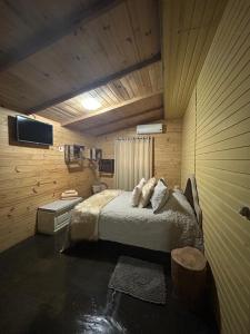 グラマドにあるMorada Pé da Montanhaのベッドと壁掛けテレビのある寝室