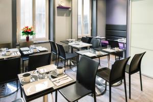 a dining room with tables and chairs and windows at Hotel des Savoies Lyon Perrache in Lyon