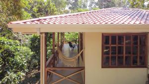 a small house with a porch with a swing at Villa Piňa dorada dependencia del hotel Casa Merlin in Puerto Viejo