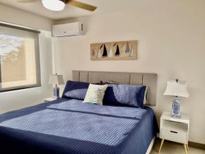 a bedroom with a blue bed with two lamps and a window at Modern Beach Apartment - Walk to Playa Mantas & Beach Club Access in Punta Leona +34 photos