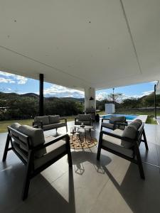ein Wohnzimmer mit Stühlen, einem Tisch und einem Pool in der Unterkunft Casa de lujo con piscina en Malacatos in Loja