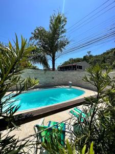 een zwembad in een tuin met stoelen en een boom bij Ancoradouro Pousada in Penha