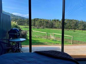 a bedroom with a bed and a view of a field at Farm Stay - Apollo Bay Tiny Stays in Apollo Bay