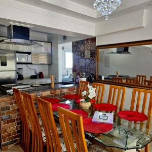 a dining room with a table and chairs and a kitchen at Requinte e sofisticação in Praia Grande