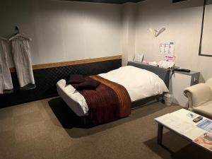 un dormitorio con una cama, una mesa y una silla en ホテルグランドール, en Mito