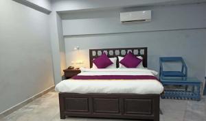 a bedroom with a bed with purple pillows and a blue chair at Villa Victor in Puducherry
