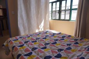 a quilt on a bed in a bedroom with a window at A mini apartment in Cuernavaca, in a good location in Cuernavaca