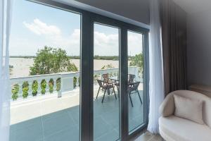 a room with a balcony with a table and chairs at Bamboo Riverside Boutique Hotel in Ben Tre