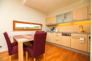 a kitchen with a wooden table and purple chairs at Papli Apartments in Pärnu