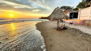a beach with two chairs and an umbrella and the ocean at 2 Casitas for 8 guests on Beach Front w Pool & AC in Pochomil