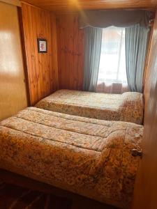 Dos camas en una habitación pequeña con ventana. en Casa Rukalma Centro, en Villarrica