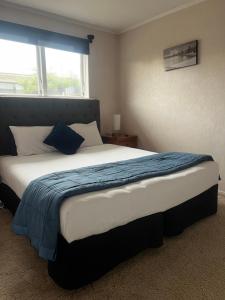 a bedroom with a large bed with a blue blanket at ASURE Surrey Court Motel Invercargill in Invercargill