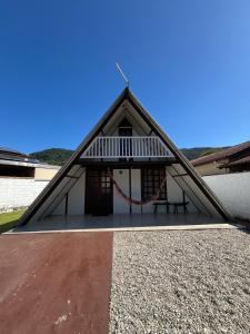 a building with a pitched roof with a picnic table at Chalé em Ubatuba para 12 pessoas com Wi-Fi in Ubatuba
