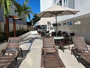 Un patio con mesas y sillas y una sombrilla. en Bela Hospedagem - Imperial Flat - Beira mar de Tambaú, en João Pessoa