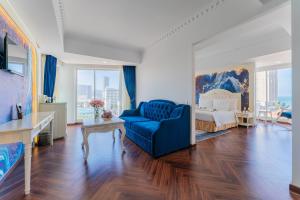 a living room with a blue chair and a bed at Nha Trang Prince Hotel in Nha Trang