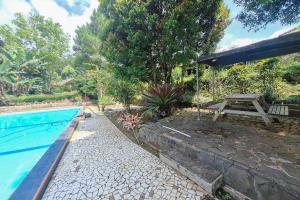 a swimming pool with a picnic table and a picnic table next to at Villa Paul Pamijahan RedPartner in Gunungpicung