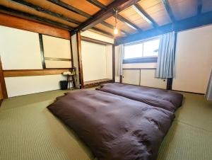 a large bean bag bed in a room with a window at 蔵サウナのある貸切古民家宿 ojirotomarlo in Tsuiyama