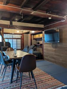 a room with a table and chairs and a television at 蔵サウナのある貸切古民家宿 ojirotomarlo in Tsuiyama