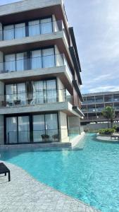 un immeuble avec une piscine devant un immeuble dans l'établissement Apartamento de Luxo no Resort GAV, Muro Alto, Porto de Galinhas, à Ipojuca