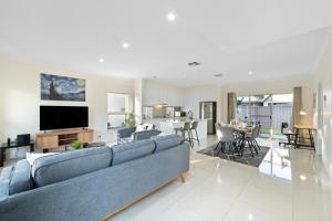 a living room with a blue couch and a kitchen at Fig & Fern - Modern Comfort between City & Coast in Glandore