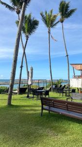 un parc avec des palmiers, un banc et des tables dans l'établissement Apartamento de Luxo no Resort GAV, Muro Alto, Porto de Galinhas, à Ipojuca
