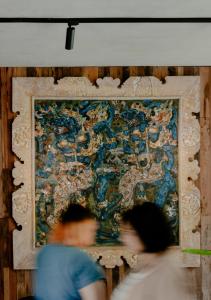 two people walking past a large painting on a wall at ARTOTEL Haniman Ubud in Ubud