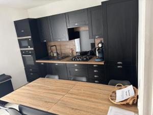 a kitchen with black cabinets and a wooden table at Les Belous in La Rochelle