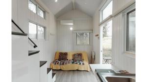 a tiny house with a couch in a room at Raintree Farmstay by Tiny Away in Sarsfield