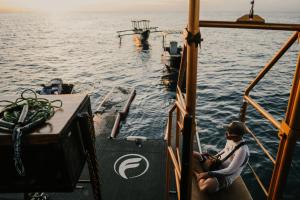 a man sitting on a boat in the water at Floating Hotel SALTWATER COWBOYS in Kuta +28 photos