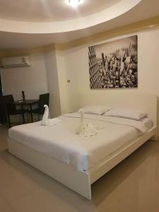 une chambre avec un lit blanc avec des cygnes dessus dans l'établissement Sea Breeze Patong Holiday Condo, à Patong Beach