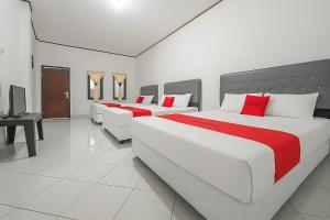 two large beds in a room with red pillows at RedDoorz at Pantai Sayangheulang Garut 2 in Cilauteureun